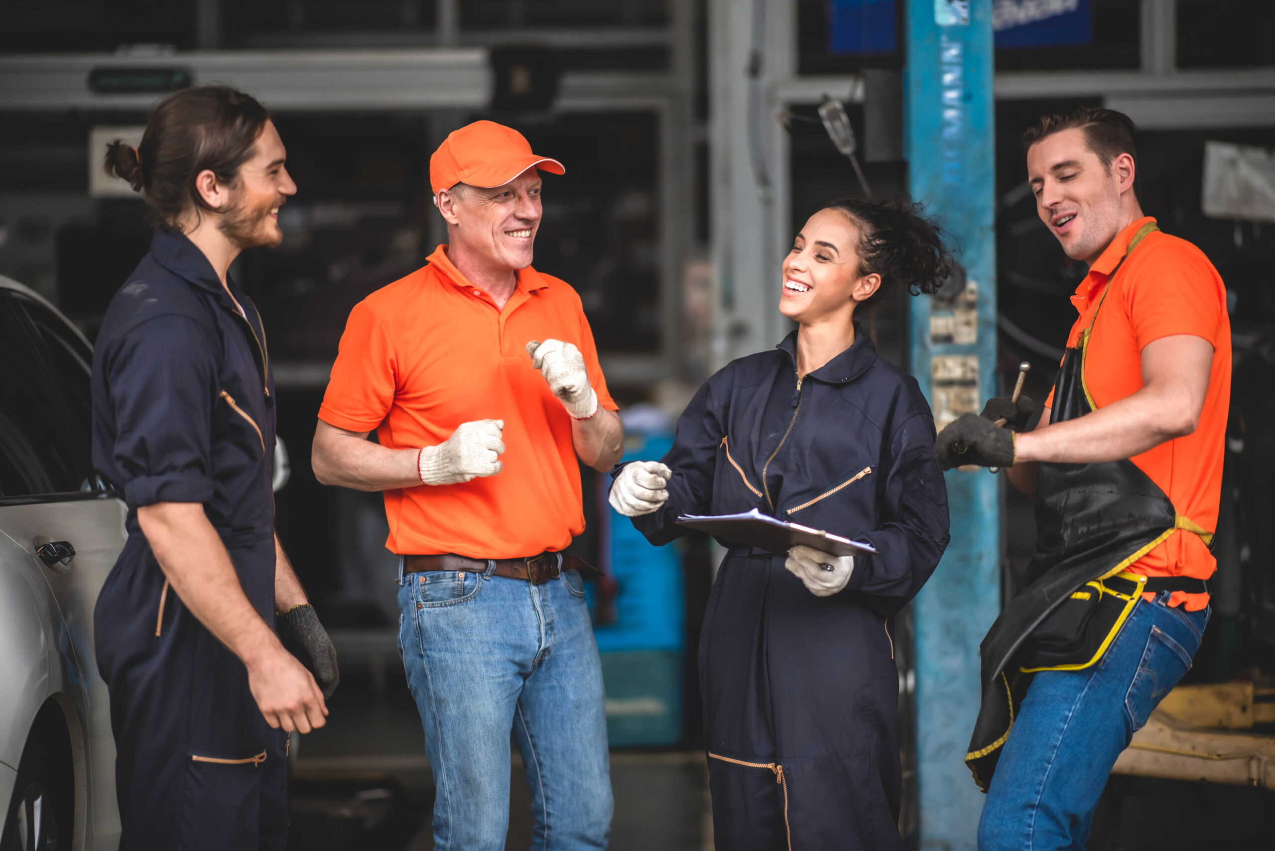 מכונאים מרוצים במוסך, מחייכים בעבודתם לאחר הפחתת עומס העבודה בעזרת בוט מוטורס AI, פתרון מתקדם המבוסס על ChatGPT לשירותי רכב.