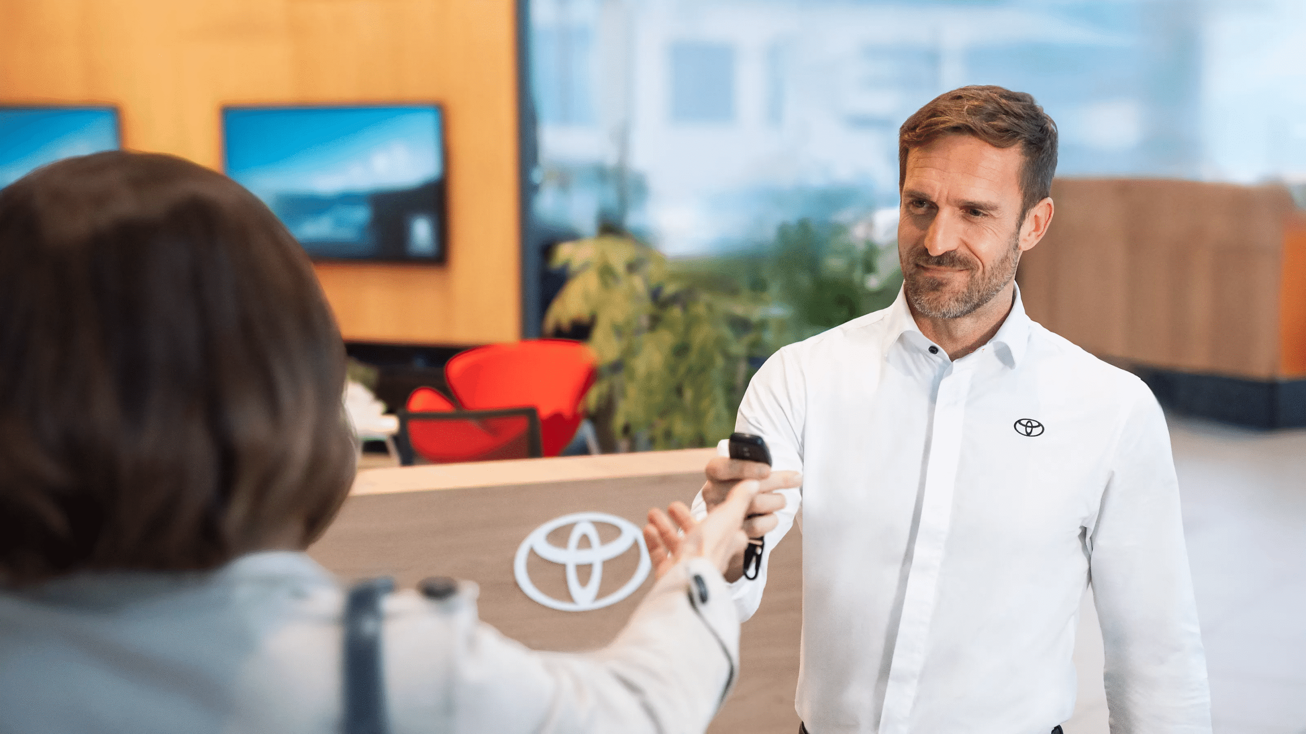 איש מכירות מציג ללקוחה הצעת מחיר באולם תצוגה, כחלק ממערכת ניהול חכמה של בוט מוטורס AI